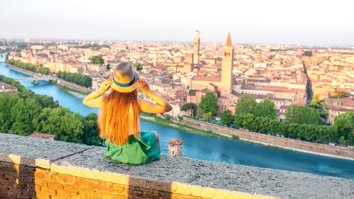 Ein Mädel sitzt auf einer Mauer und schaut auf Venetien herab.