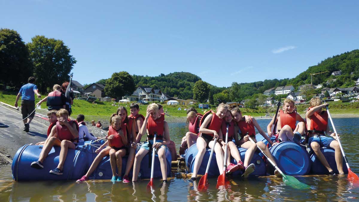 Eine Gruppe Schüler sitzt auf Flößen auf dem Rursee