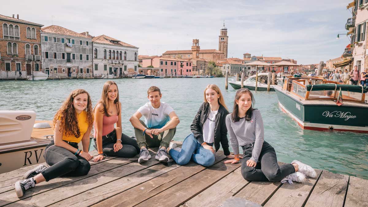 Schüler sitzen auf einem Steg in Venedig