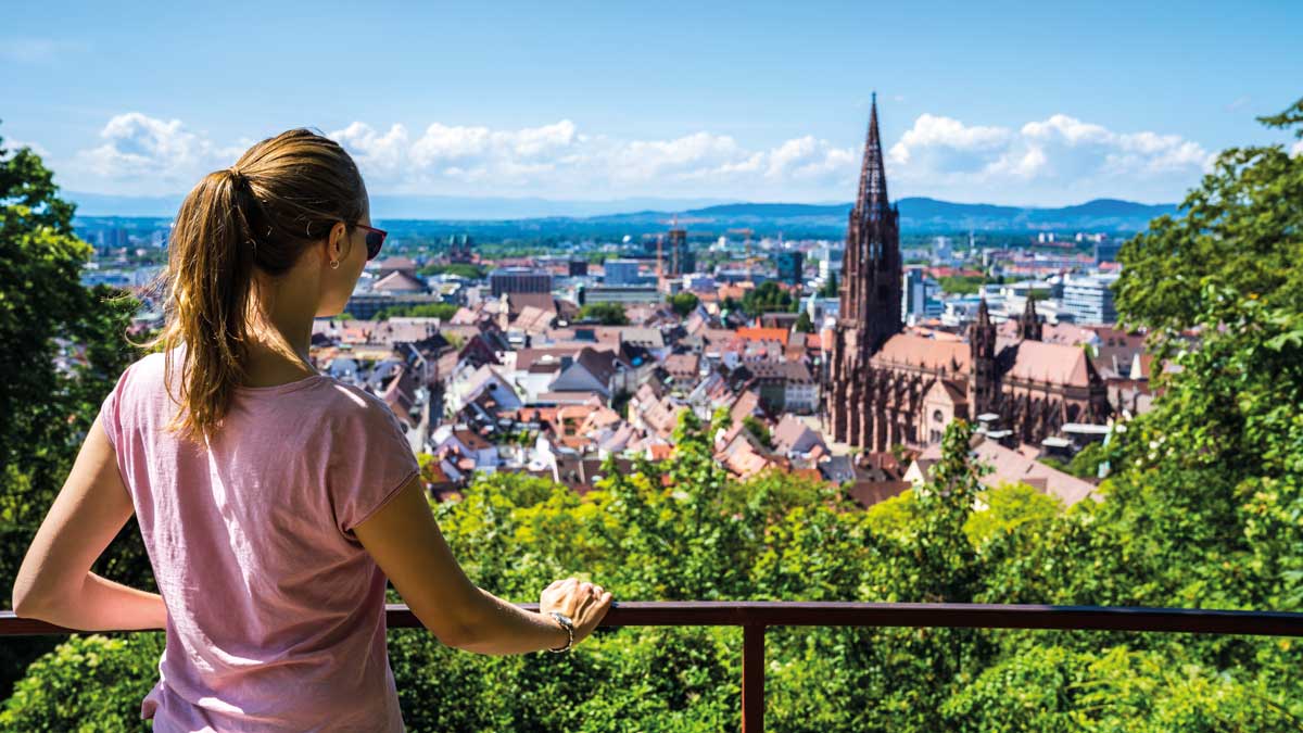 Schülerin auf einem Aussichtpunkt schaut über Freiburg