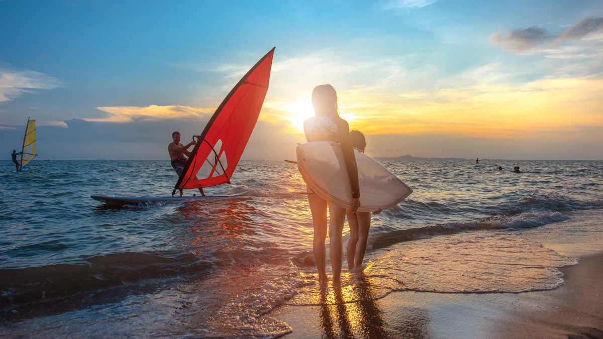 Schülerin mit Surfbrett am Strand