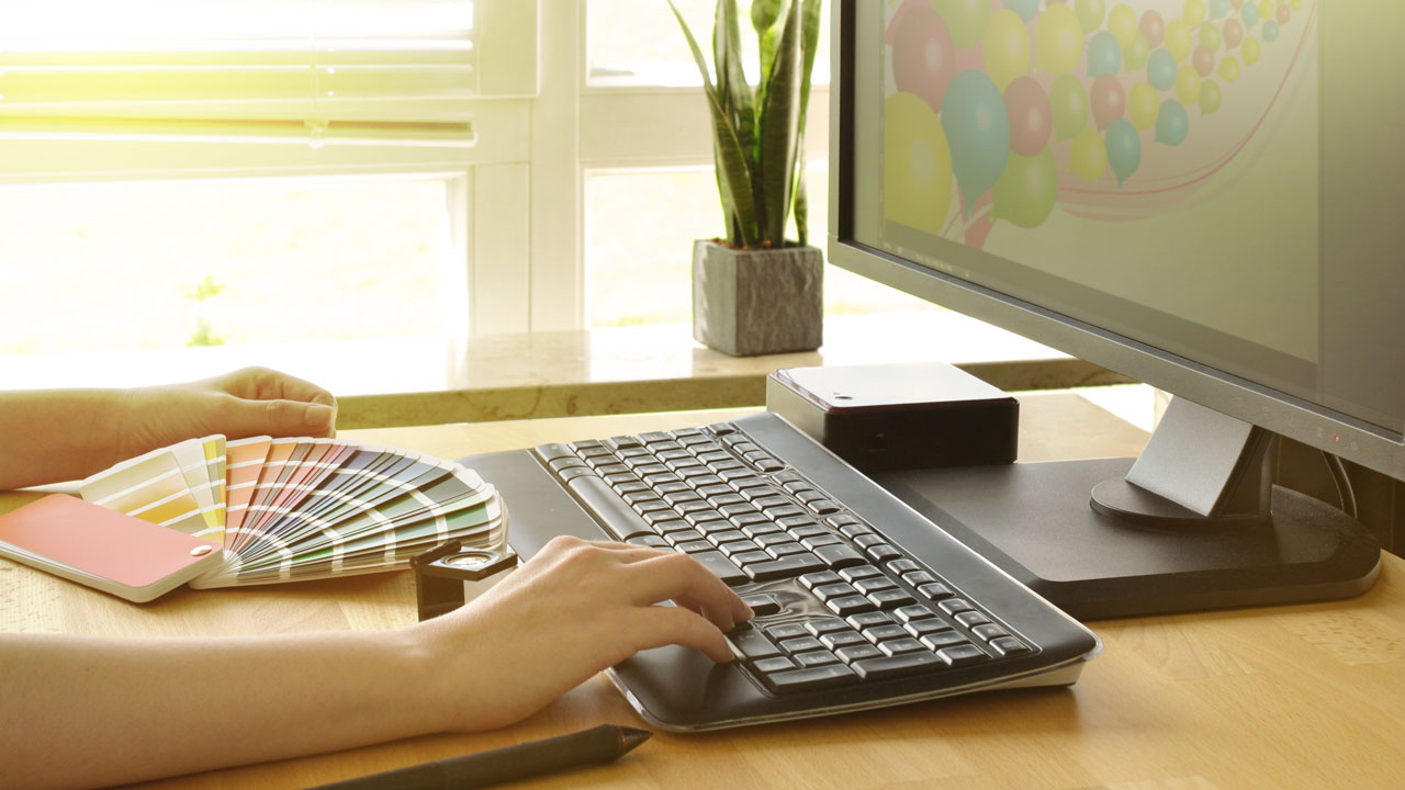 Produktmanager Deutschland Neuer Mitarbeiter mit Farbfächer und Tastatur arbeitet an Mediengestaltung.